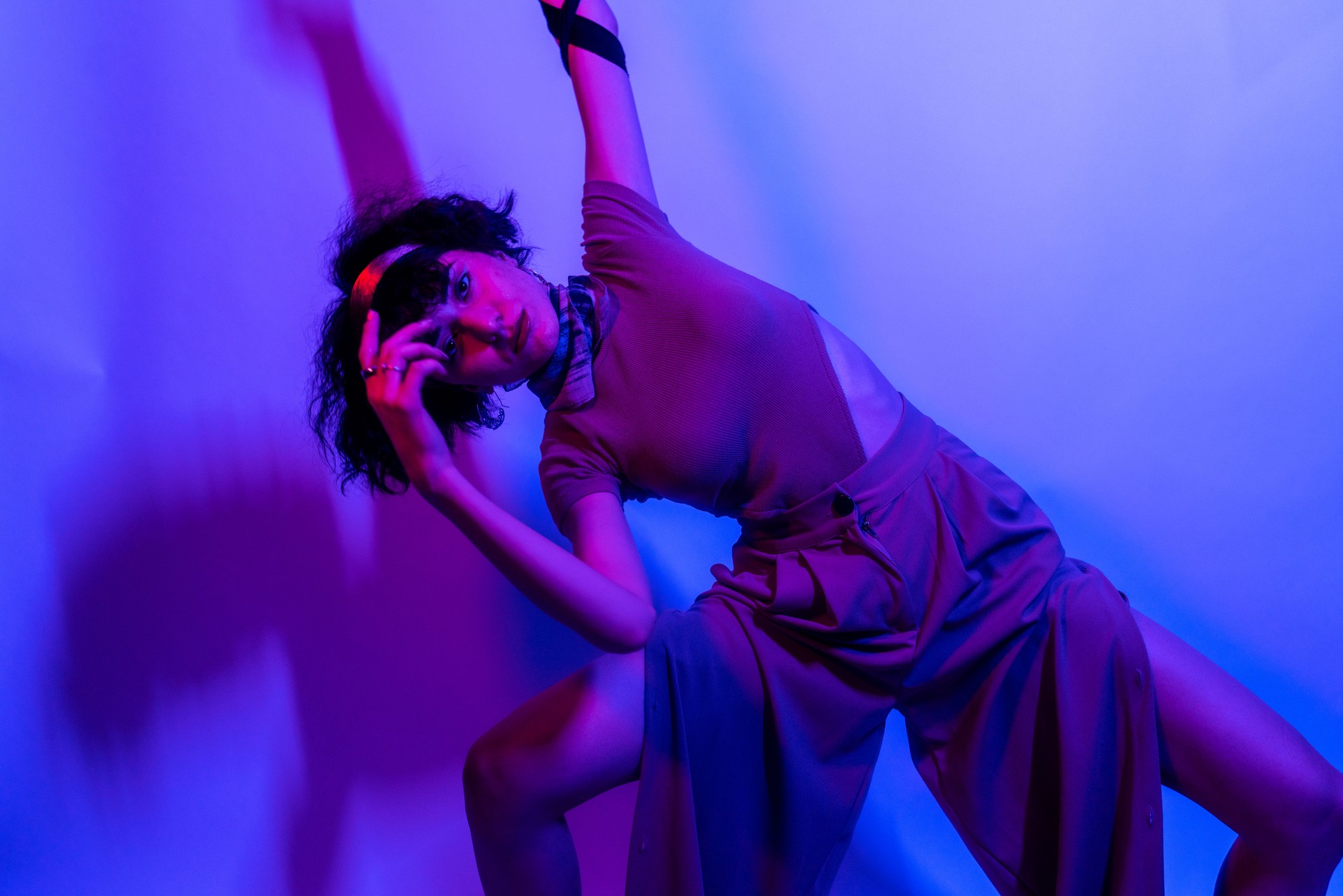 Portrait of a stylish young girl, cool dancing and with developing hair, on a neon background. High quality photo